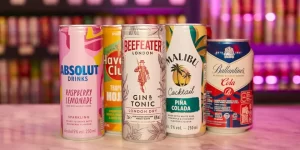 Bebidas ready to drink com iluminação rosa e com um bar de fundo