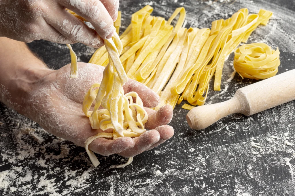 close up chef making pasta near rolling pin