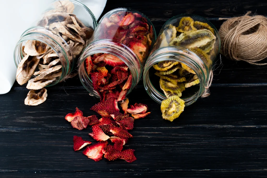 side view various dried fruit slices scattered from glass jars black background 1